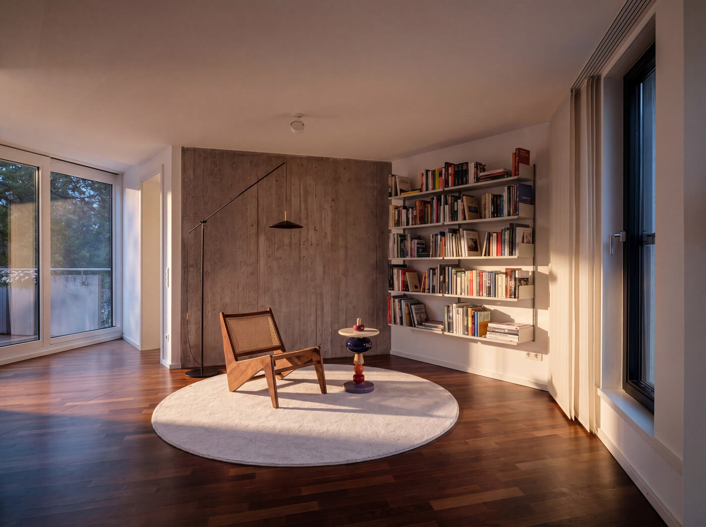 Wohnzimmer mit Bücherregal und Sessel in Wohnung W.10 im Baudenkmal REDUKT 