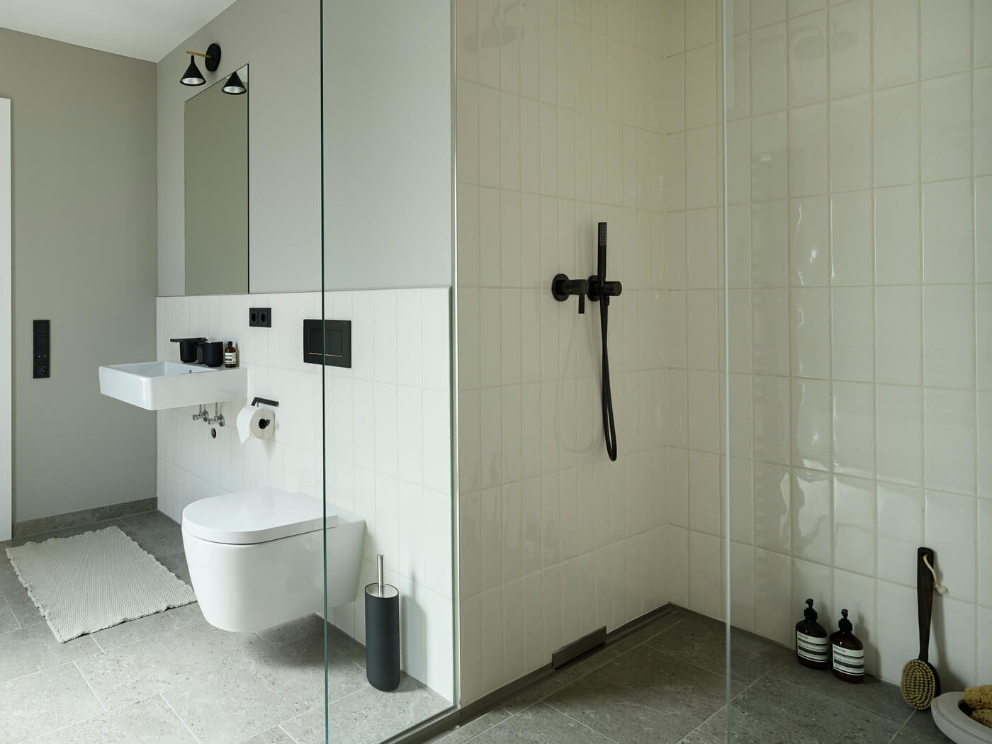 Bad der Wohnung D.03 im Haus D des Neubauquartiers kupa in München-Pasing mit bodengleicher Dusche, weißen Fliesen und modernen Armaturen