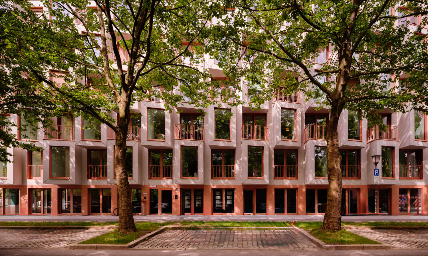 Fassadenansicht des Neubaus Van B München-Schwabing mit Bäumen im Straßenraum