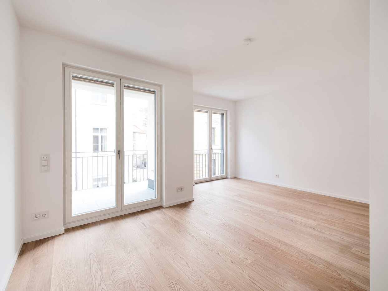 Wohnraum mit Balkon und großen Fenstern in Mietwohnung 33 im Neubau K63, München