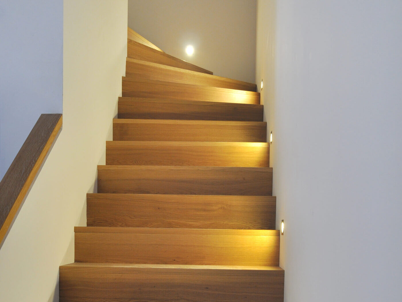 Beleuchtete Holztreppe ins 1. OG der Maisonette-Wohnung am Sebastiansplatz.