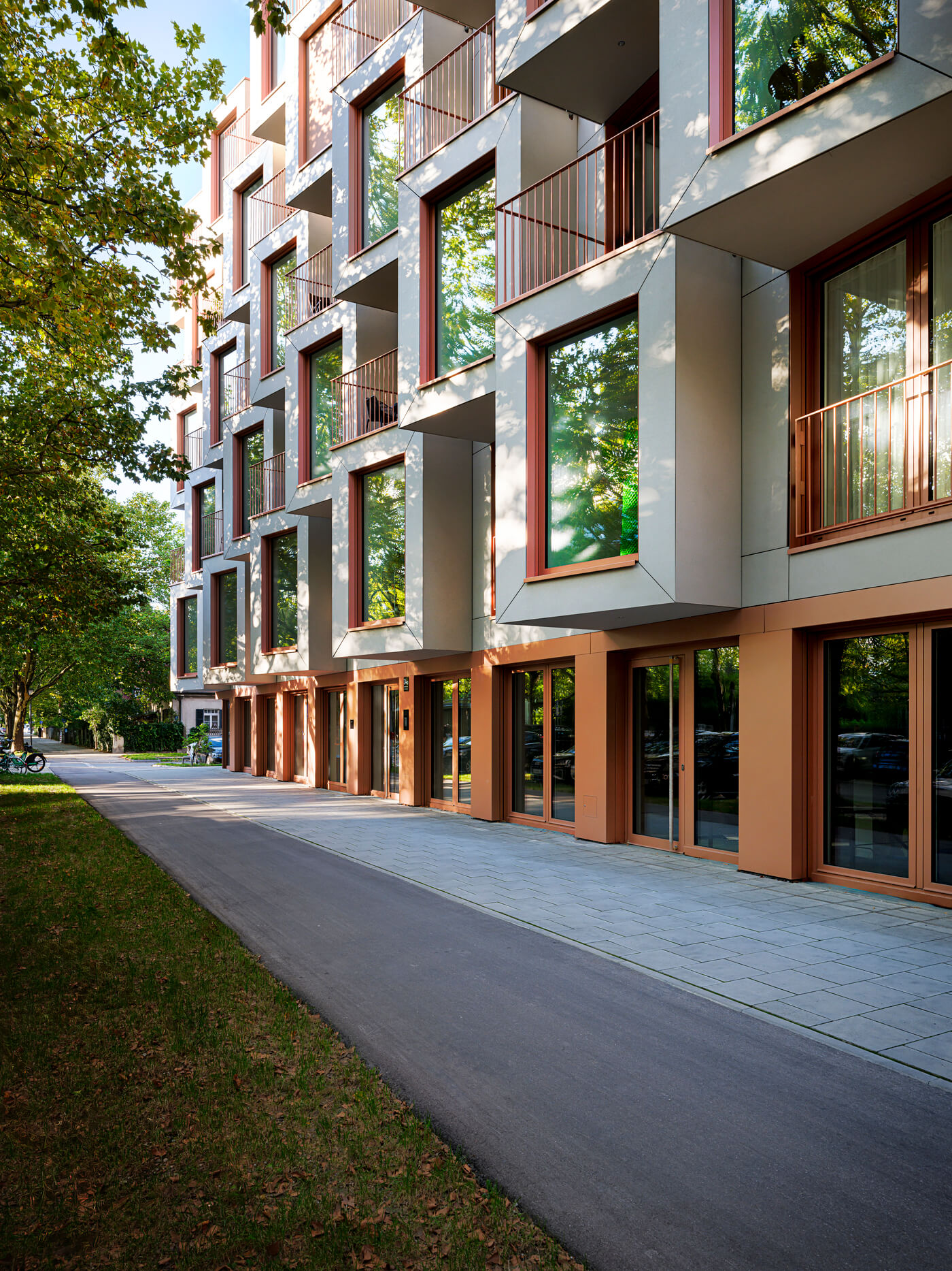 Fassadenansicht des Neubaus Van B in München-Schwabing mit Grünstreifen & Bäumen