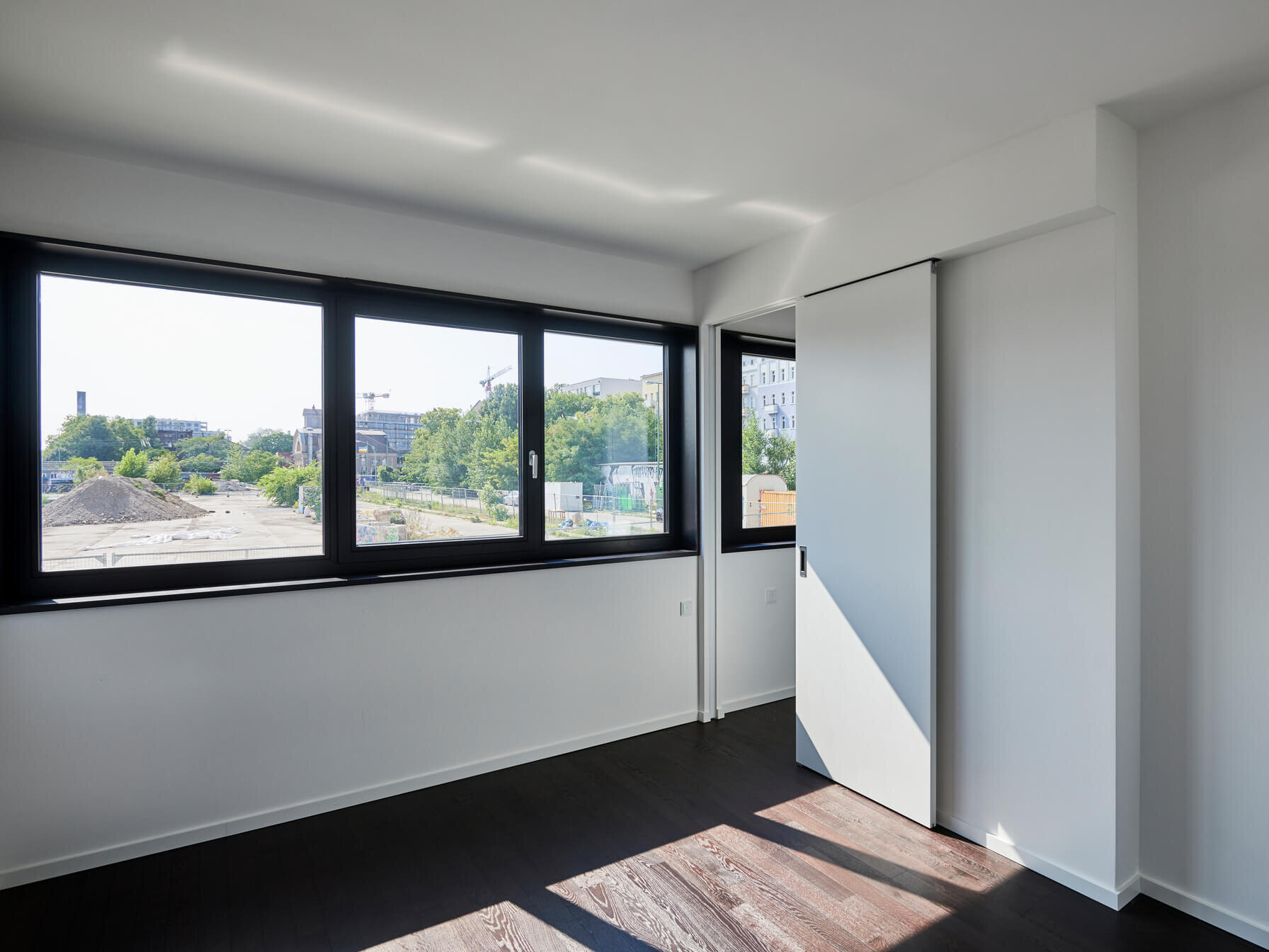 Innenraum Mietwohnung E.38 WAVE Berlin mit Fenster und dunklem Eichenparkett