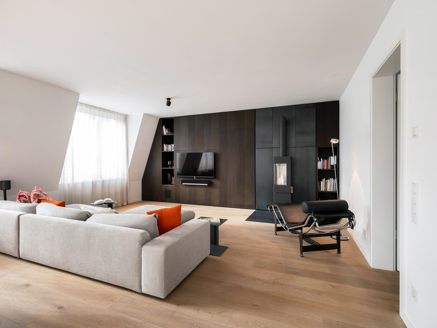 Wohnbereich der Eigentumswohnung W1.16 mit großzügiger Couch und Echtholzkamin