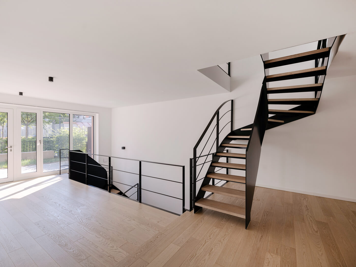 Wohnbereich mit Terrasse und Galerietreppe im Neubauprojekt Van B in München-Schwabing
