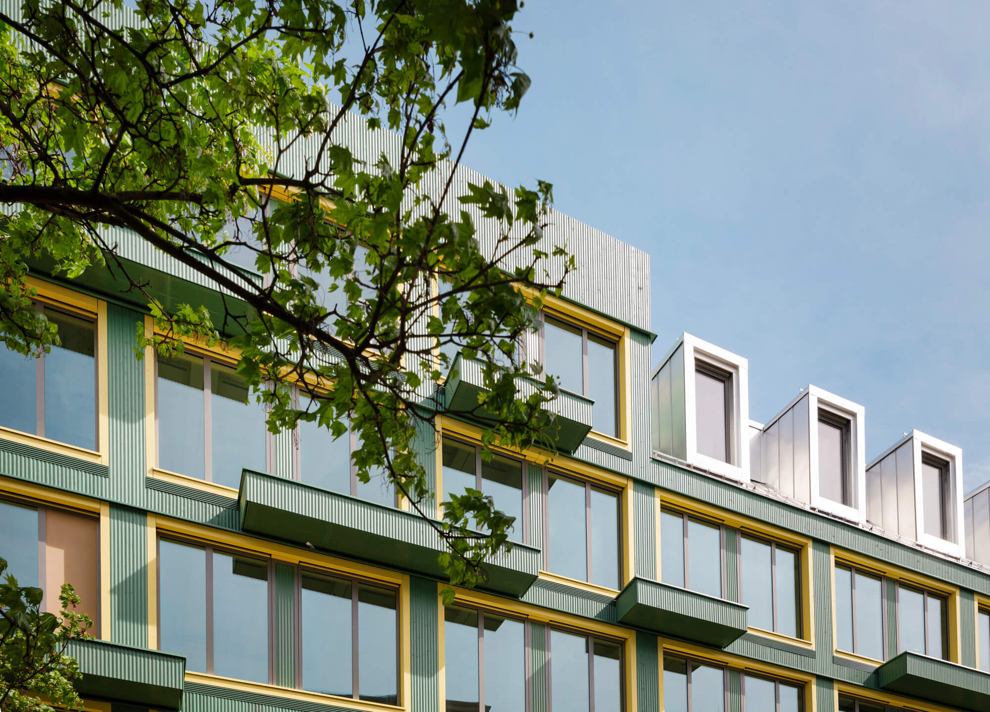 Holzfassade mit Balkonen vor Bäumen des Neubaus VINZENT, München-Neuhausen