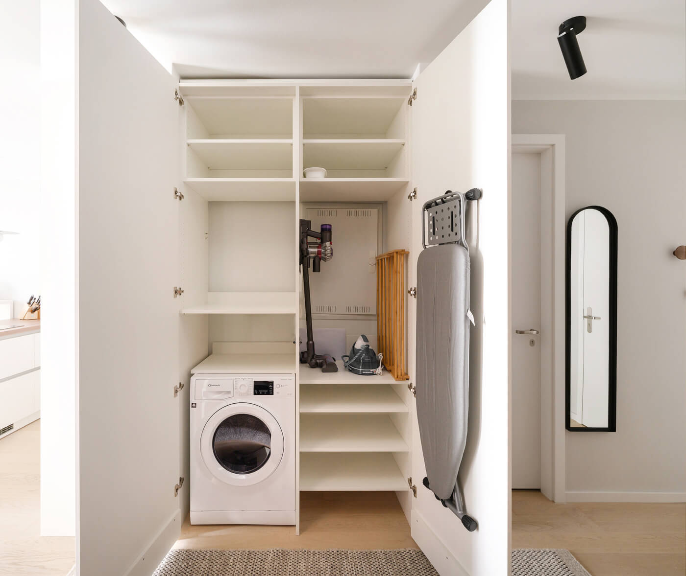 Offen gestalteter Hauswirtschaftsschrank mit Waschmaschine und Stauraum.