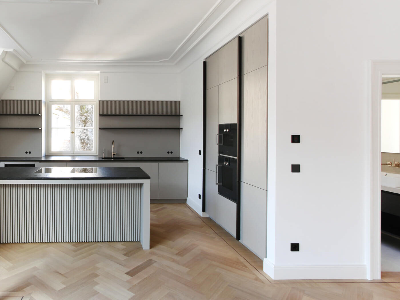 Einbauküche mit Kochinsel und Fischgrätparkett in der Villa Amalie, München