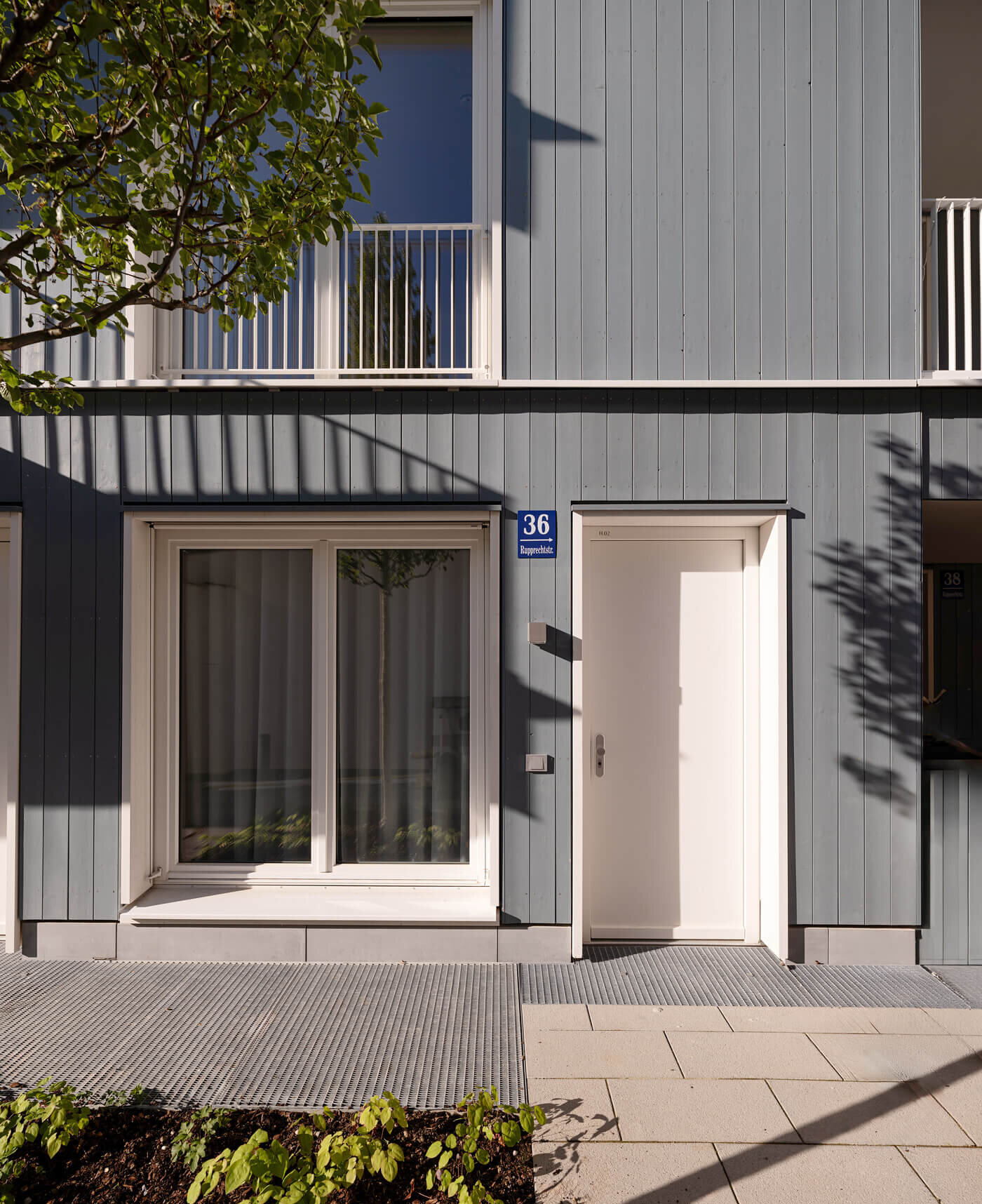 Holzfassade mit Eingangstür der Garten-Maisonette im Neubau VINZENT, Neuhausen