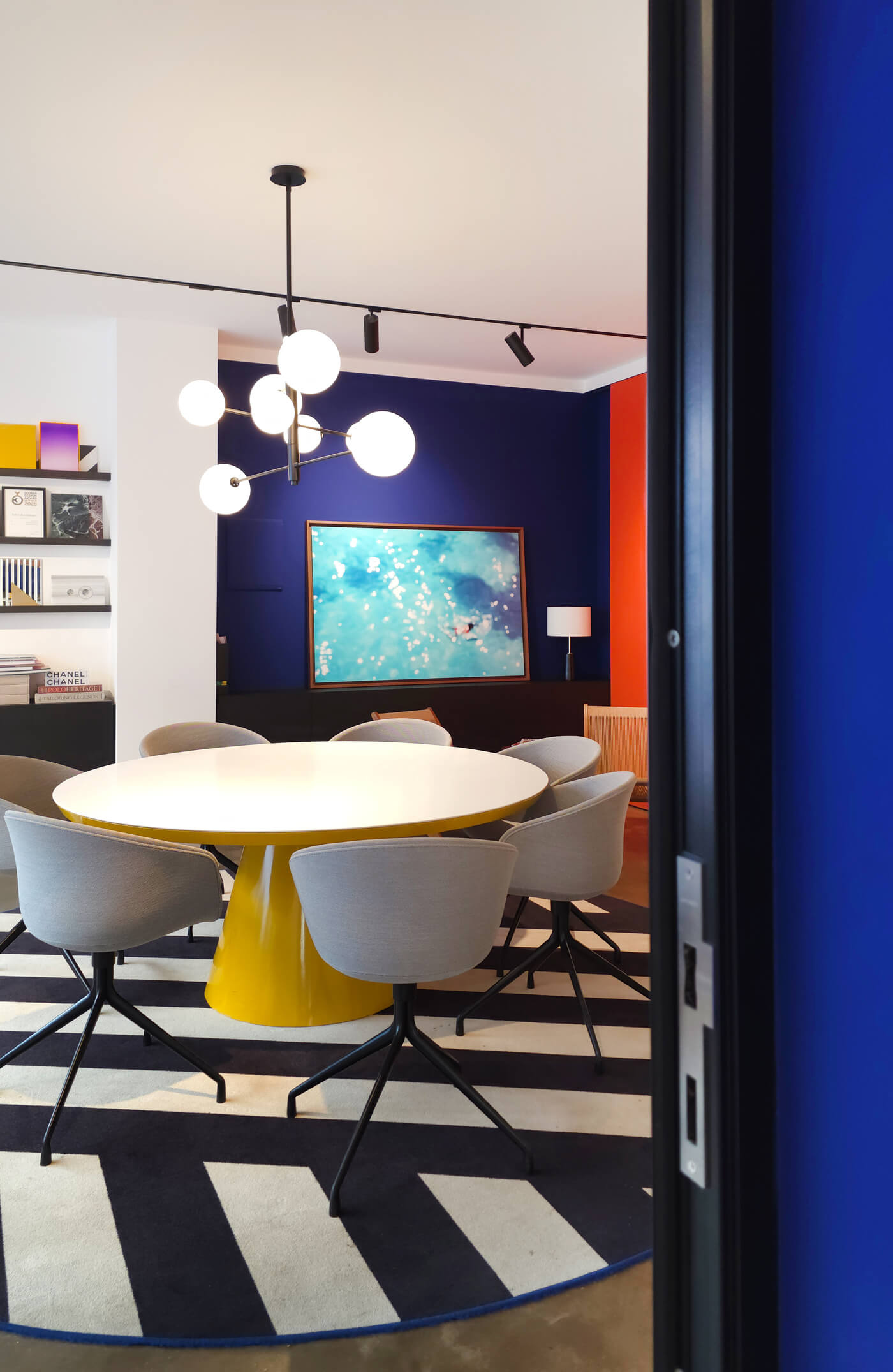 Runder Tisch mit Stühlen unter Pendelleuchten in farbigem Showroom