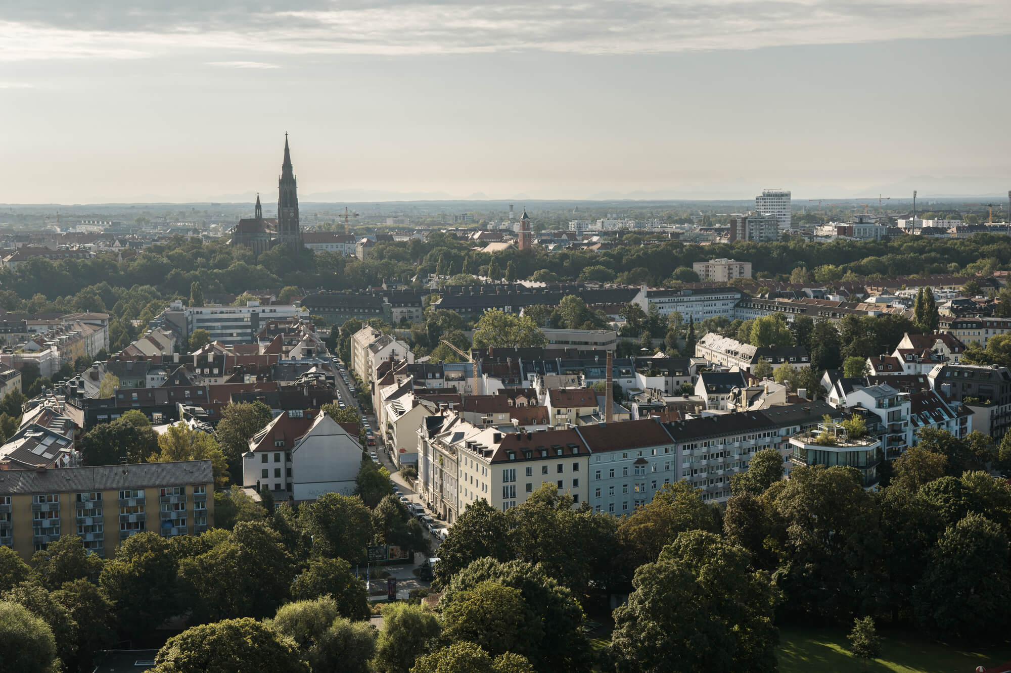 Panorama über Untergiesing in München mit Blick auf das Wohnviertel, dem Isarpark und dem Turm der Heilig-Kreuz-Kirche nahe Neubauprojekt Haus Claude