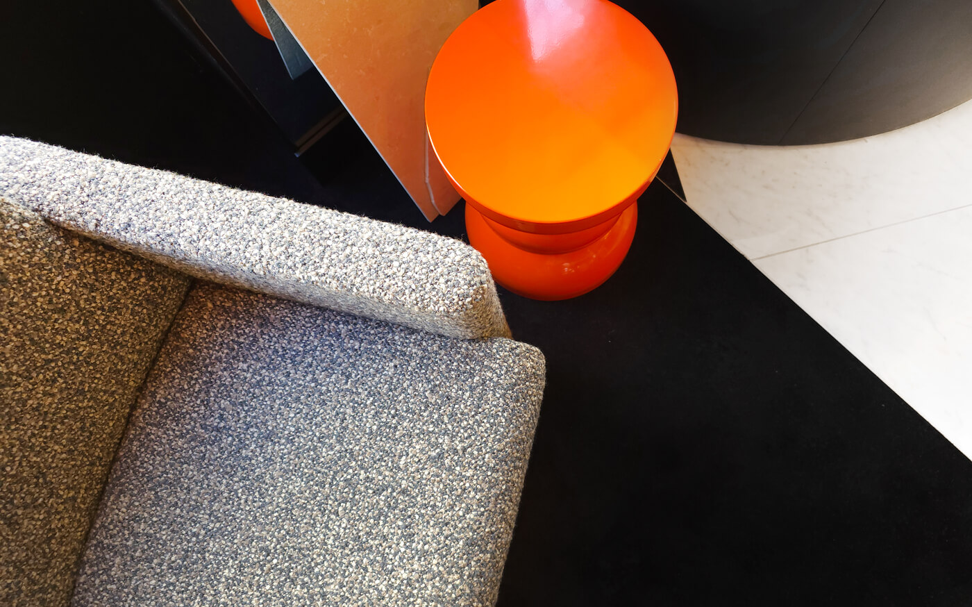 Grauer Sessel und orangefarbene Lampe auf schwarz-weißem Boden