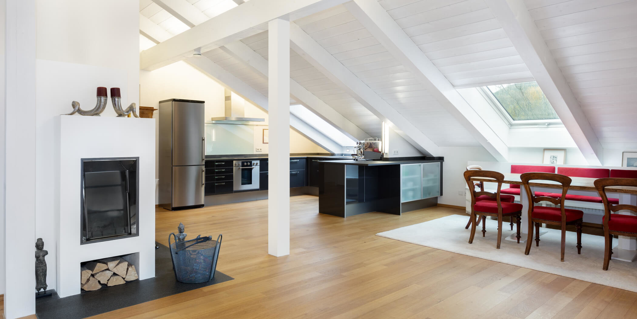 Offener Wohn-, Ess- und Küchenbereich der Dachgeschosswohnung im Landhaus Wallbergblick in Rottach-Egern mit Kamin und Essplatz unter Dachschrägen