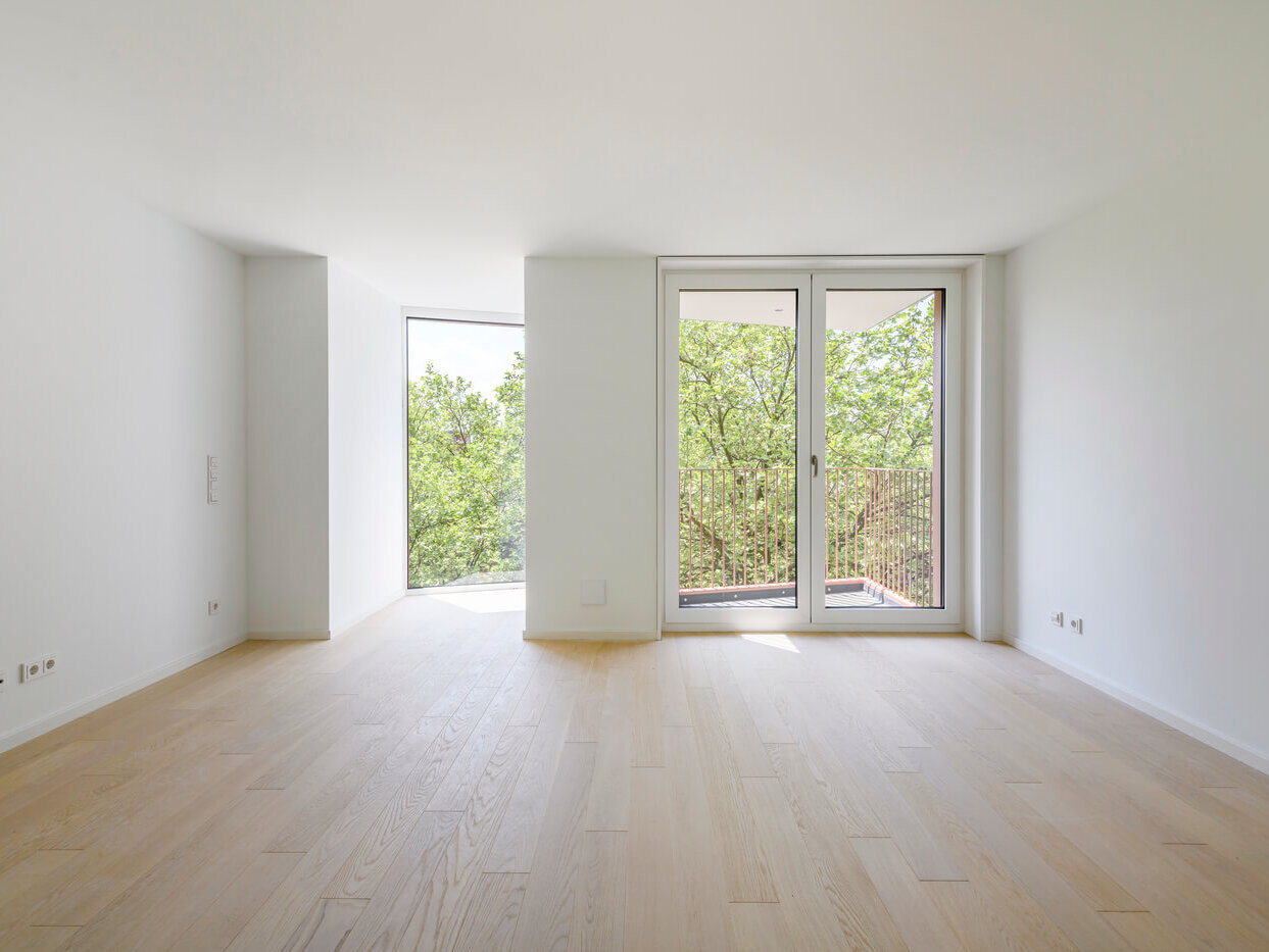 Wohnraum mit Balkon und Fenstern in Apartment A.108 im Neubau Van B in Schwabing