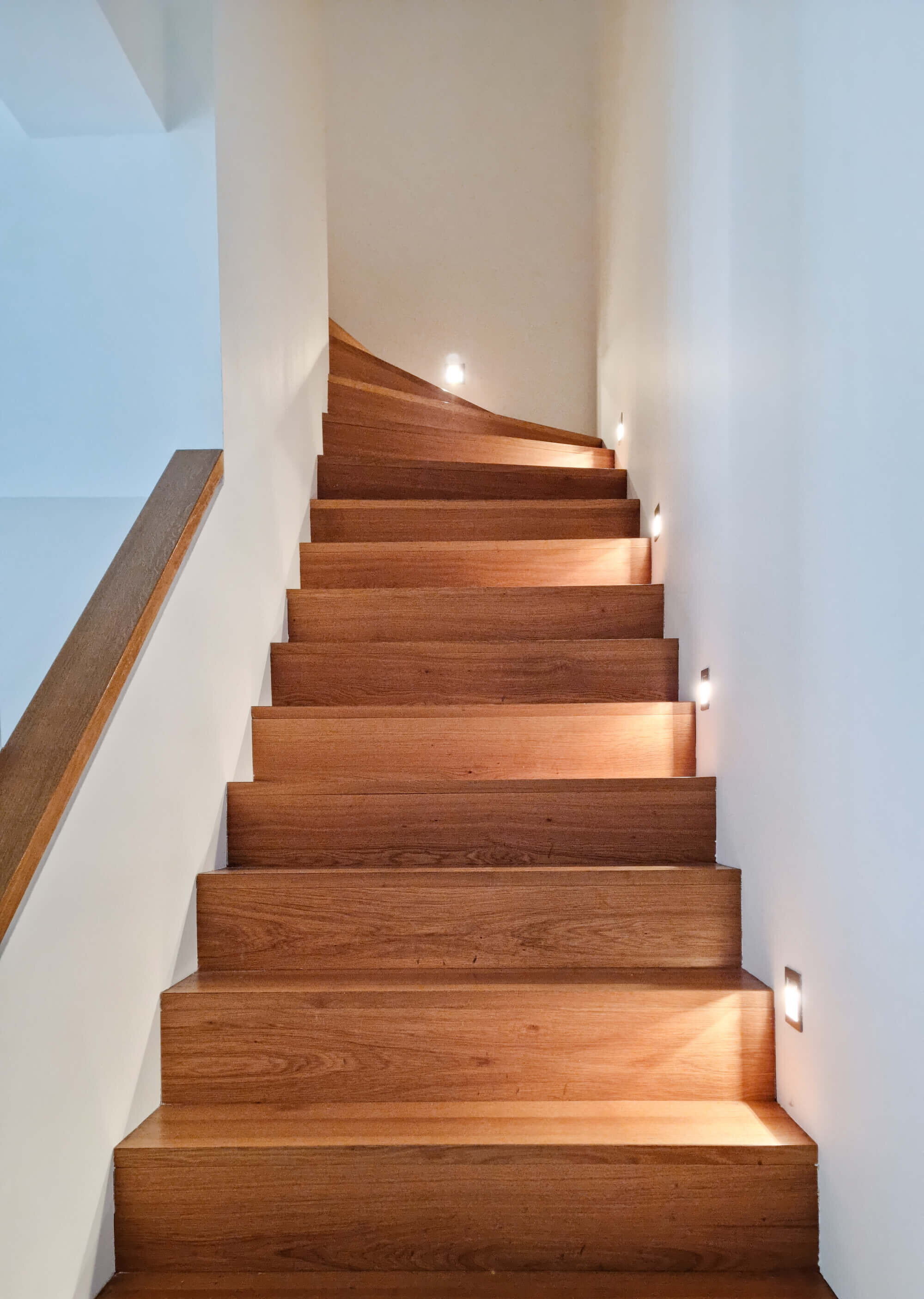 Beleuchtete Holztreppe ins 1. OG der Maisonette-Wohnung am Sebastiansplatz.