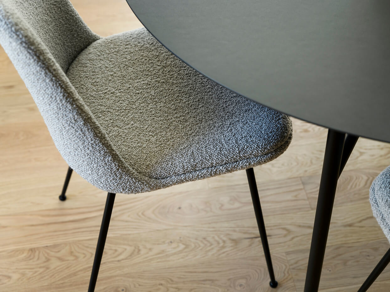 Wohnzimmer der Wohnung D.03 im Haus D des Neubauquartiers kupa in München-Pasing mit Detailaufnahme Polsterstuhl am Esstisch auf Parkettbode