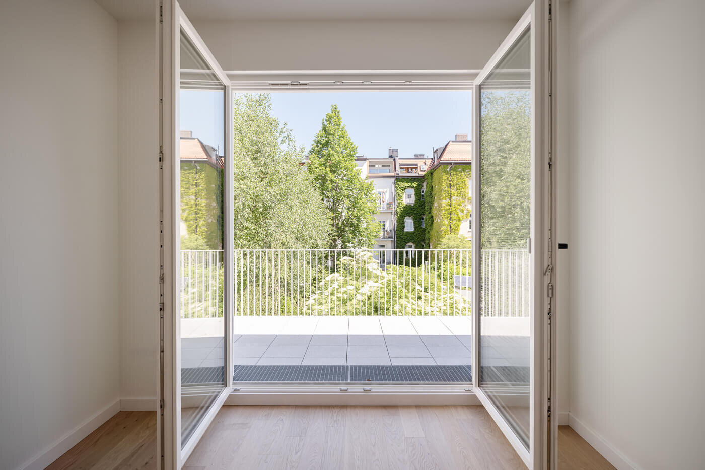 Zimmer mit Blick auf Balkon und Bäume in Wohnung H.17 im Neubau VINZENT, München