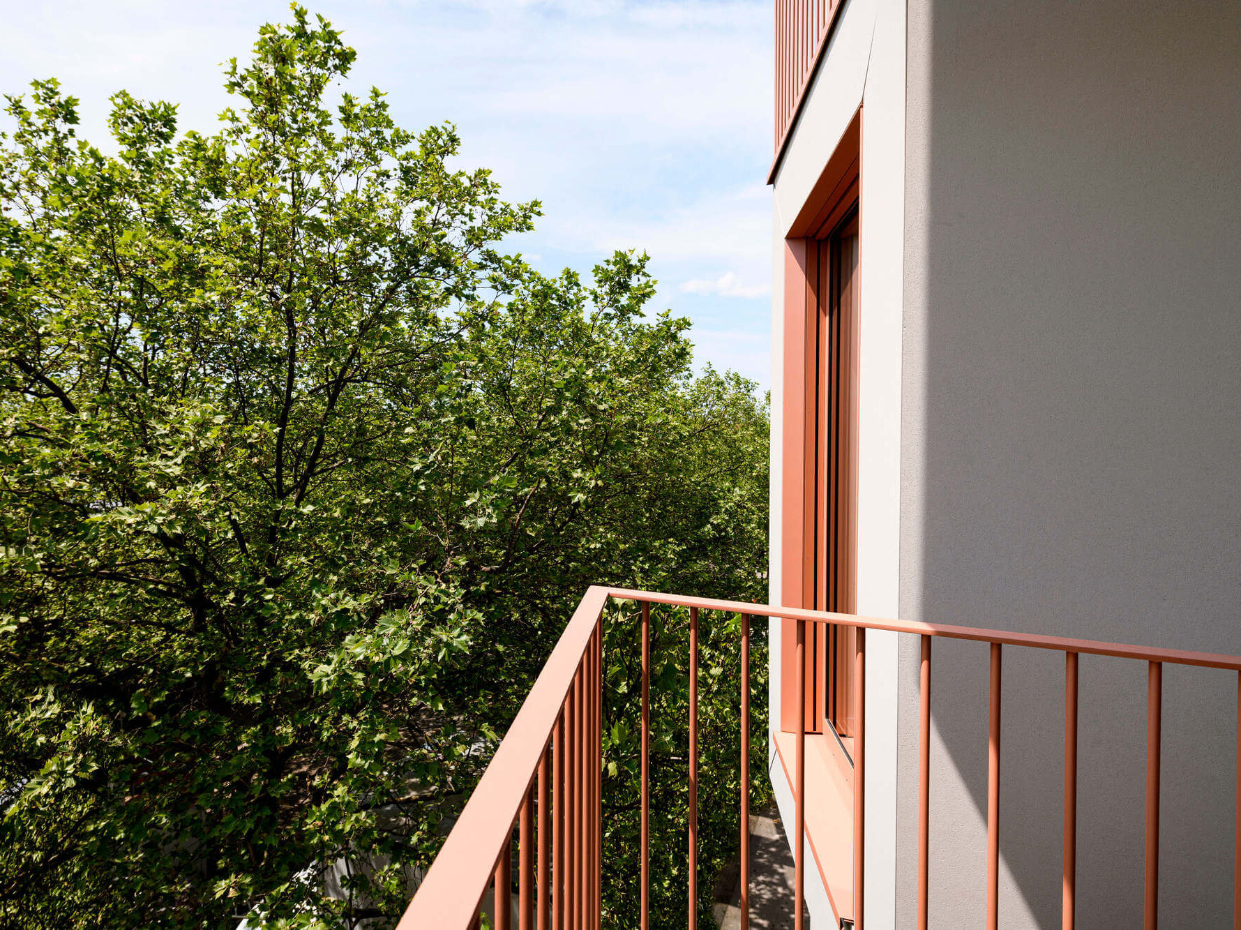 Balkon der Mietwohnung A.85 vor Bäumen im Neubau Van B, München Schwabing