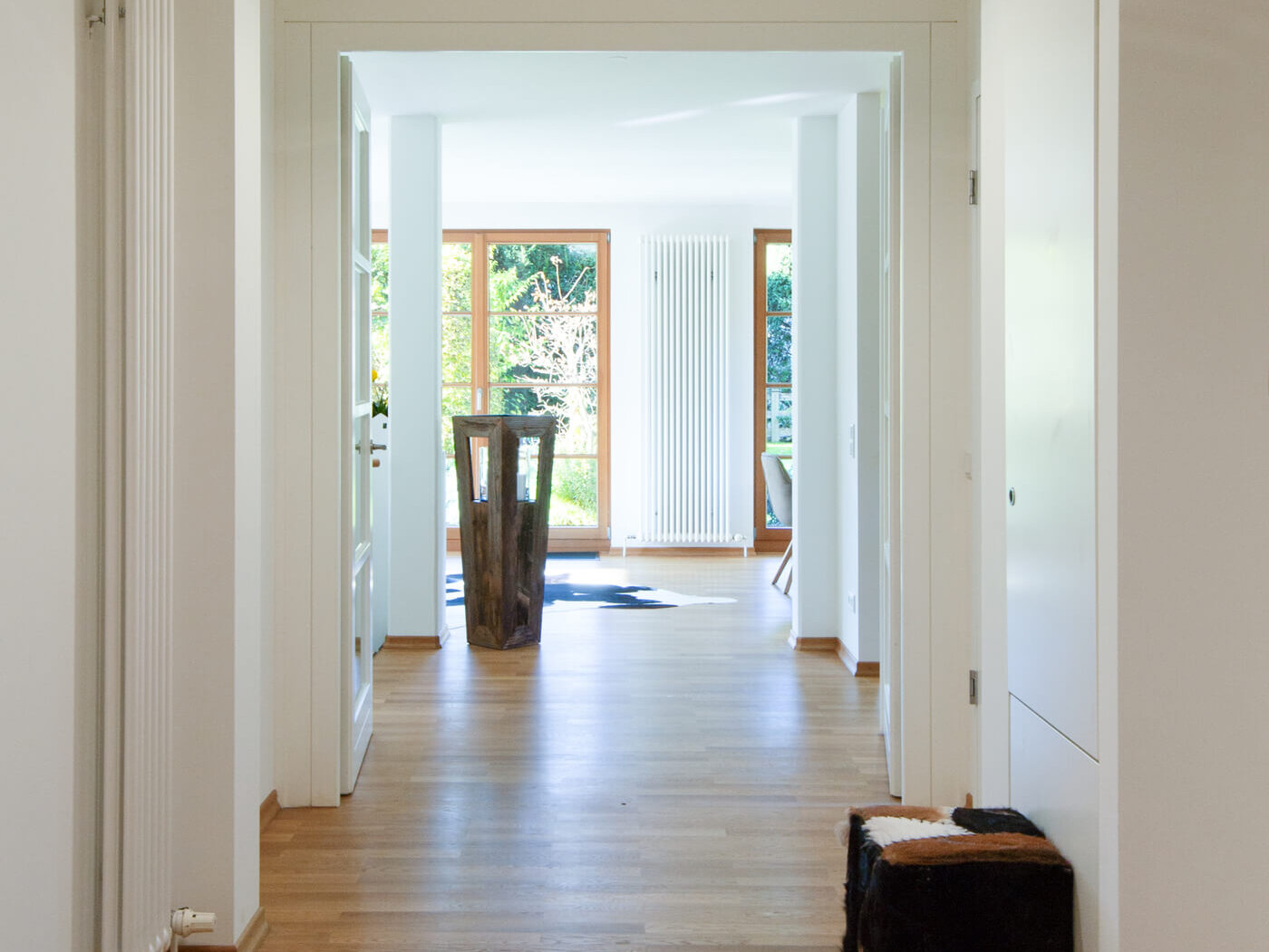 Flur der Mietwohnung 02 im Landhaus Wallbergblick in Rottach-Egern mit hellem Parkettboden, Blick in den Wohnbereich und Garten.