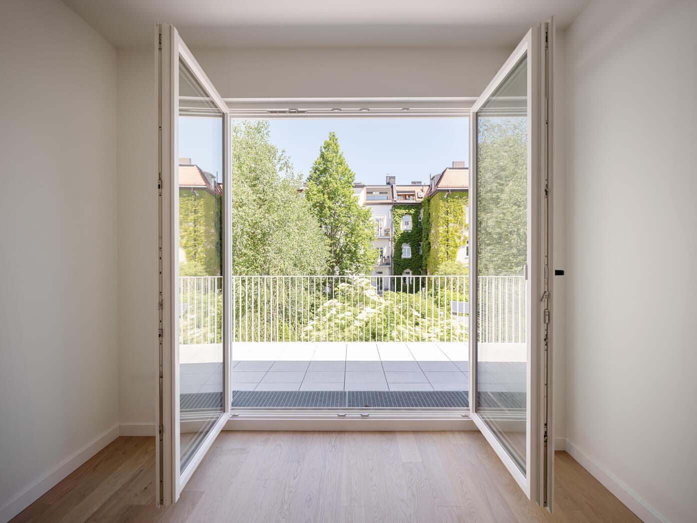 Zimmer mit Blick auf Balkon und Bäume in Wohnung H.17 im Neubau VINZENT, München