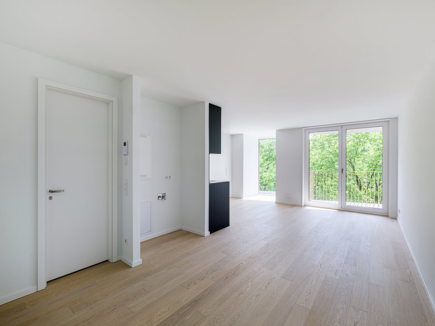Wohnraum mit großen Fenstern und Balkon in Apartment A.110 im Neubau Van B