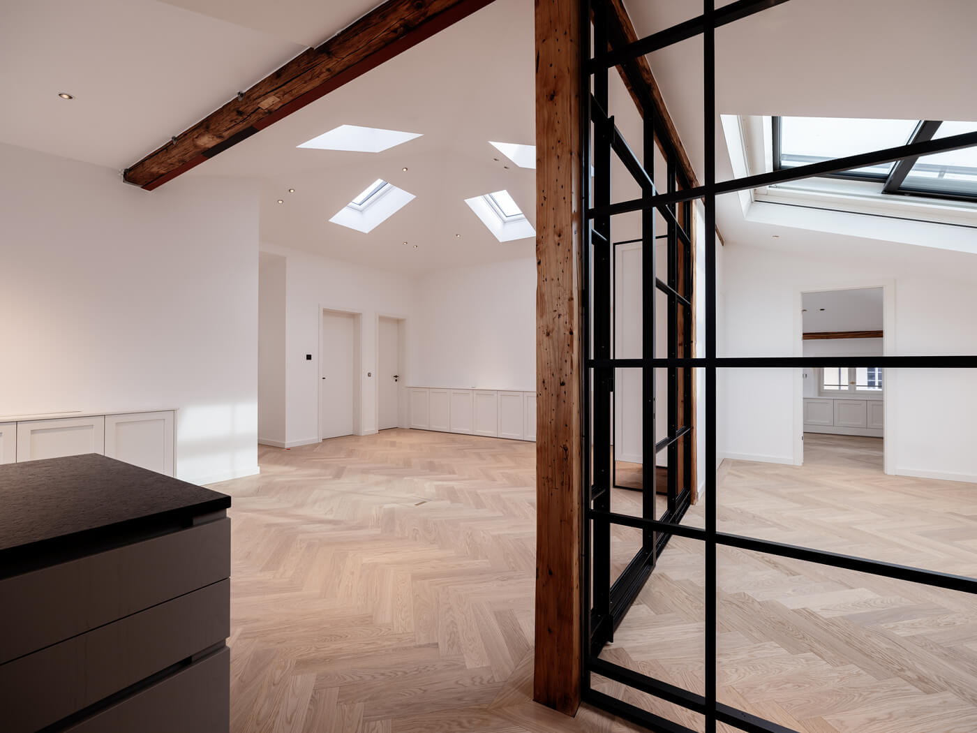 Helle Bürofläche im Ensemble Amalie mit Glaswand, Holzbalken und Dachfenster