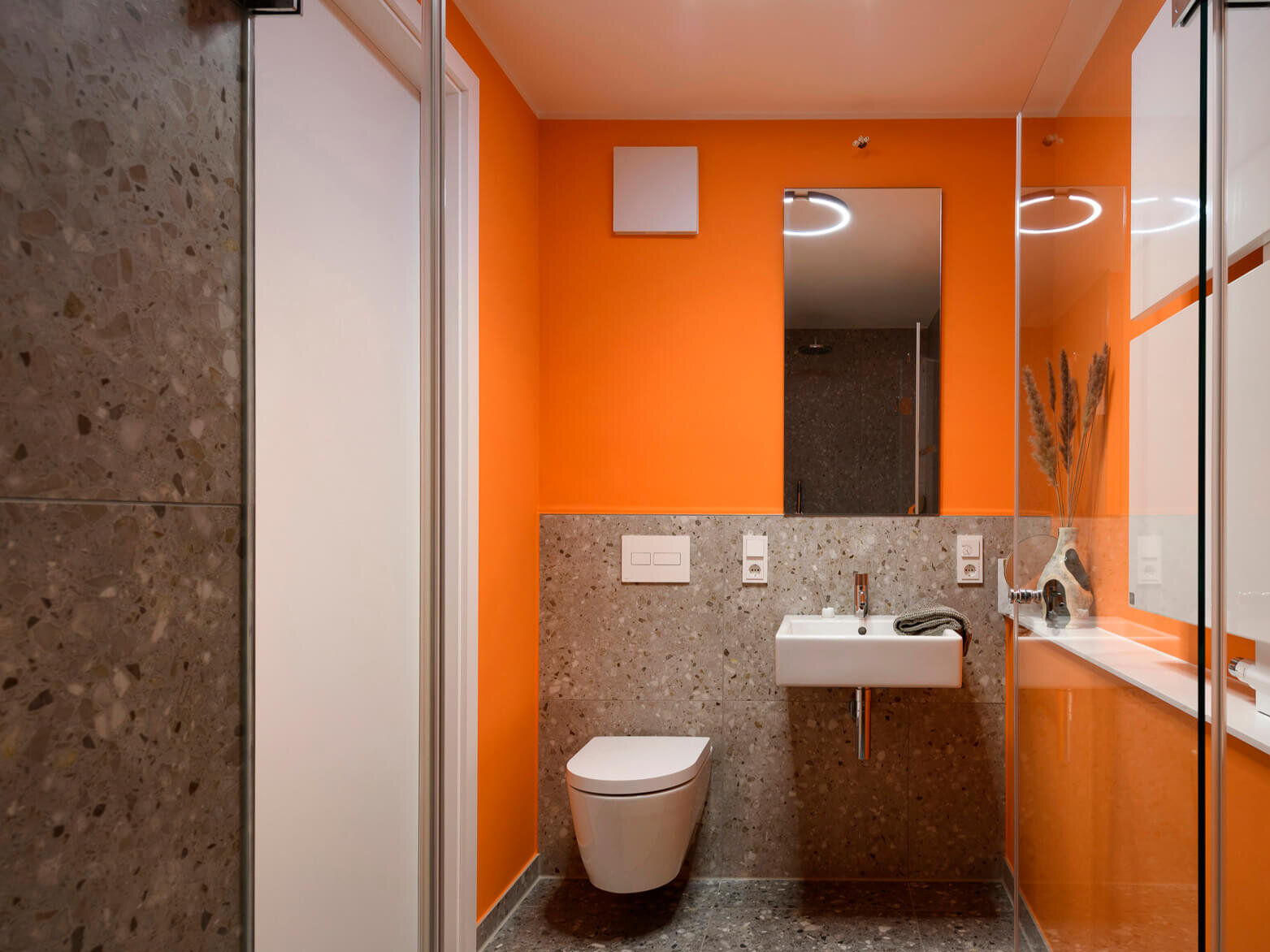 Bad mit Terrazzofliesen und orangefarbenen Wänden im Neubau Van B, Schwabing